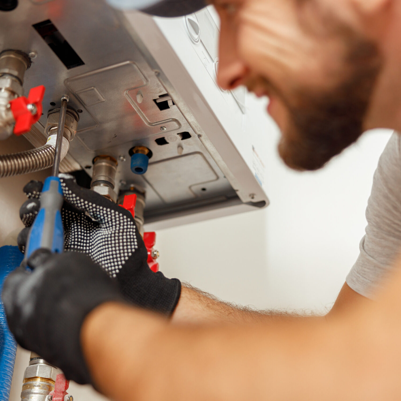 Closeup of plumber using screwdriver while installing new steel hot water central heating system in apartment. Manual work, maintenance, repair service concept